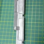 Imagen de bisagra de tapa frontal KC24B 757, fabricada con materiales resistentes para un ajuste preciso y duradero en máquinas de costura.